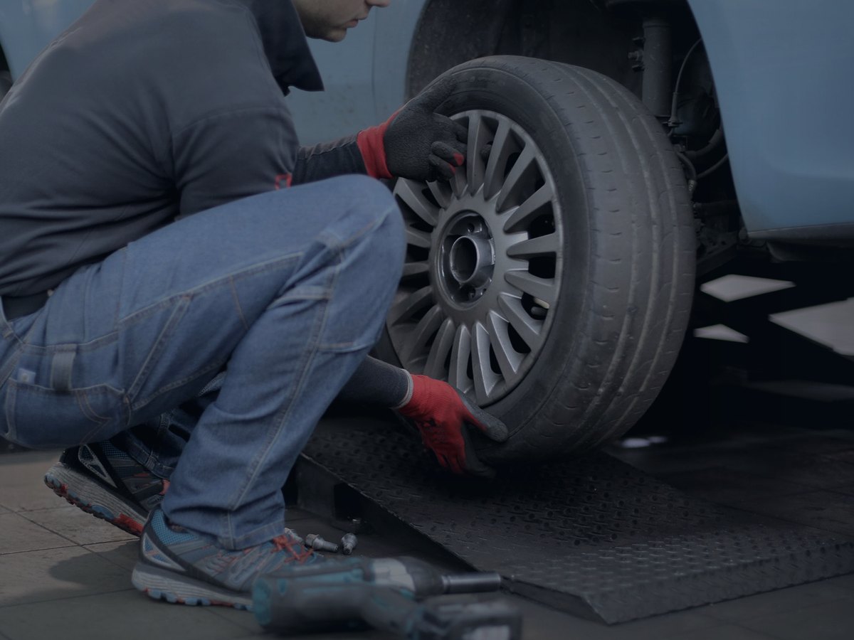 Mechanic fitting a wheel on a car in a workshop