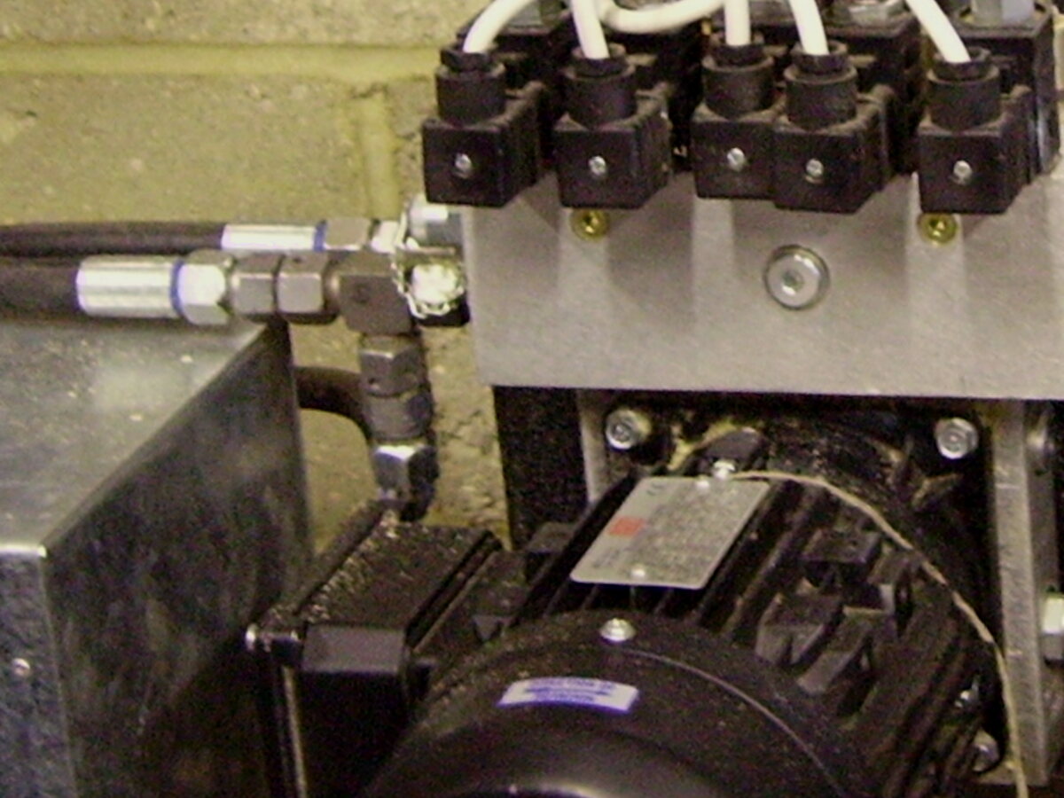 Black hydraulic hose with a crimped metal fitting on a hydraulic block